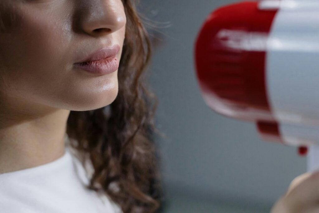 Close-up of a woman speaking toward a red assistive hearing device used for communication support.