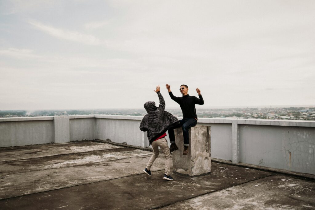Two young people giving a high five on a rooftop celebrating achievement, friendship, and positive support.